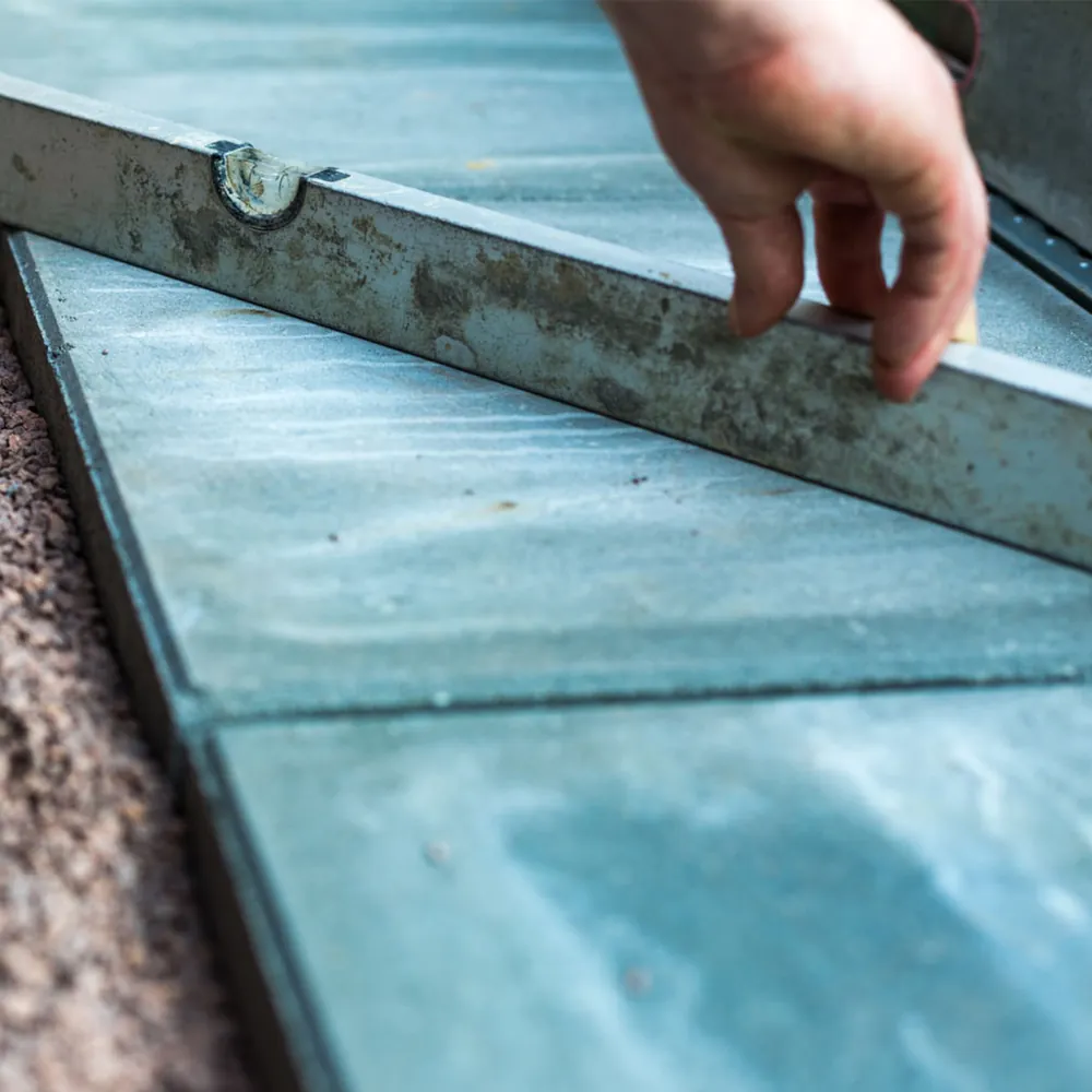 Eine Hand richtet eine Wasserwaage auf Terrassenplatten aus