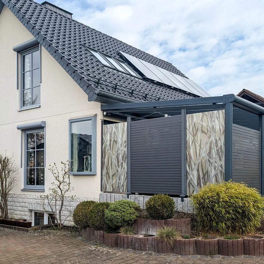 Haus mit Terrasse hinter WPC-Feldern und Glas